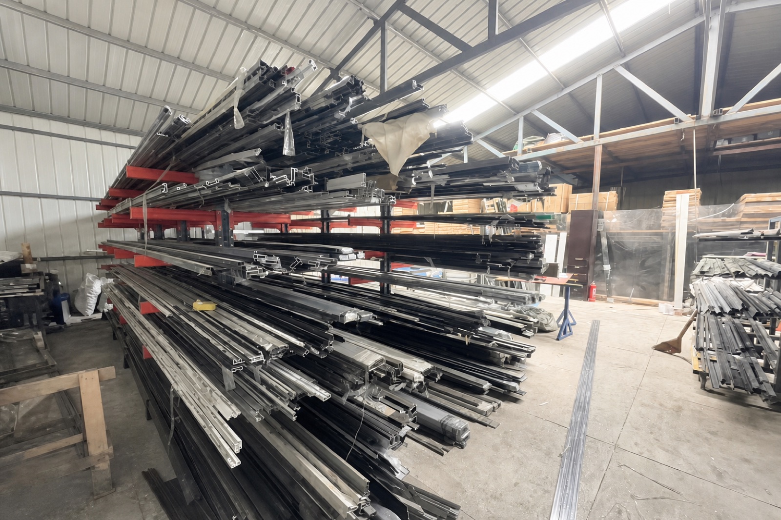 哈尔滨米格门业道外工厂店型材库房：断桥铝与铝塑铝门窗型材分类码放在货架上